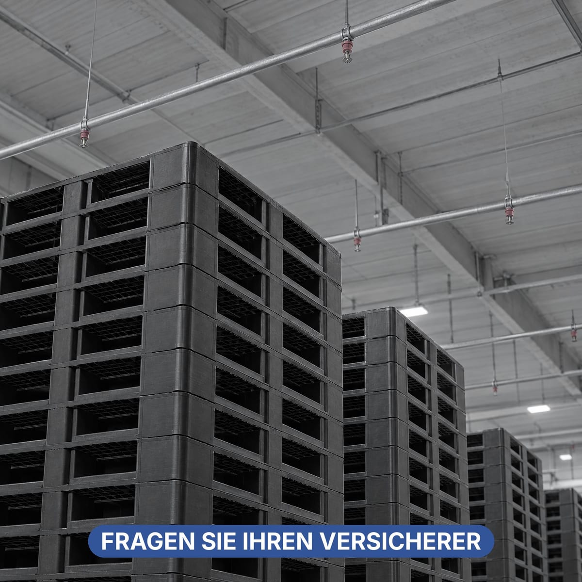 Lager mit leeren, gestapelten Kunststoffpaletten unter einer Sprinkleranlage an der Decke