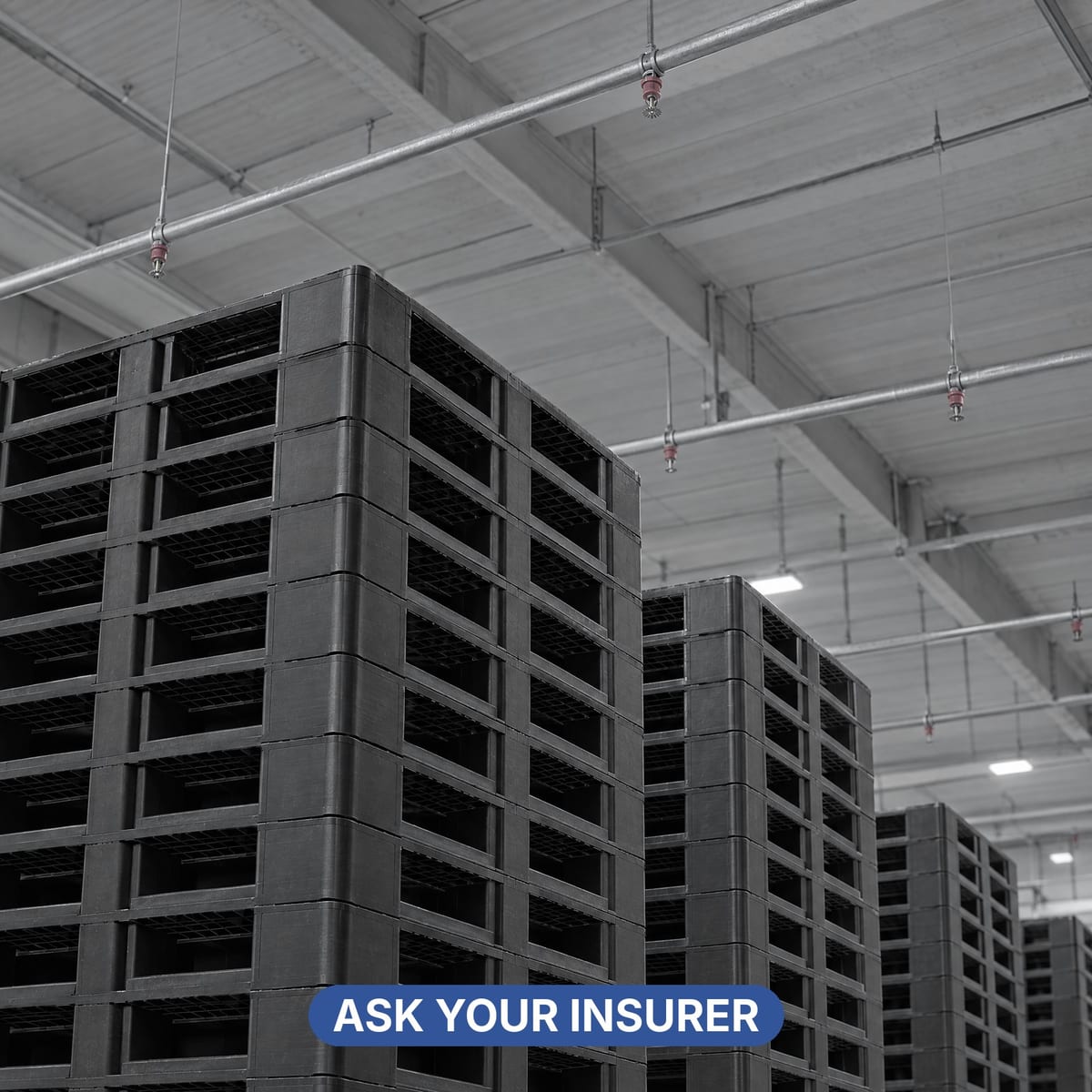 Store of empty plastic pallets stacked under a ceiling sprinkler system