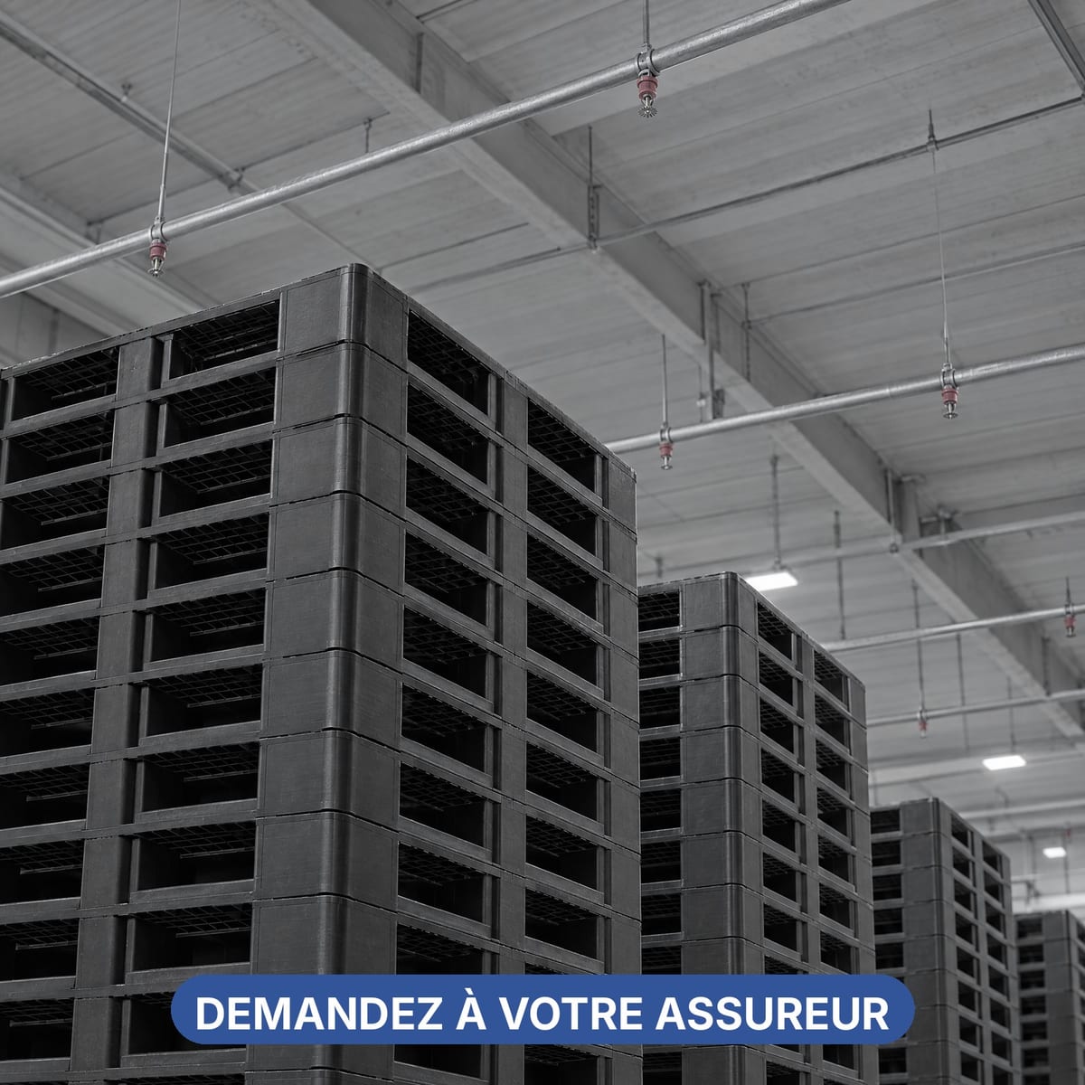 Stockage de palettes plastique vides empilées sous une installation de sprinklers au plafond
