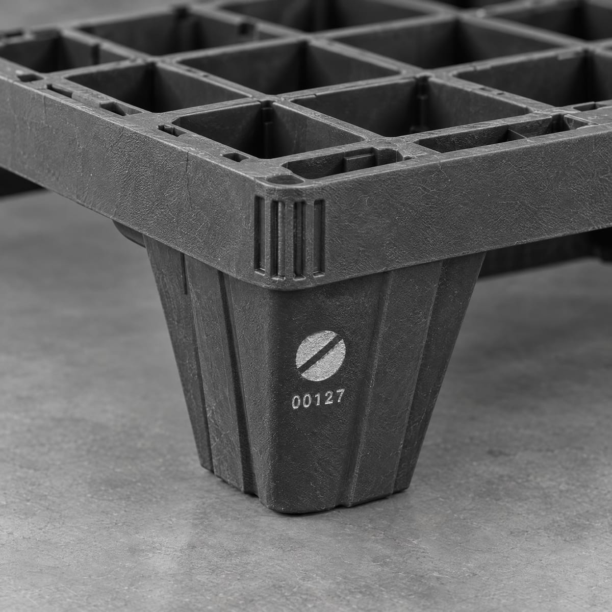 Corner of a black plastic pallet with a hot-stamped company logo and serial number