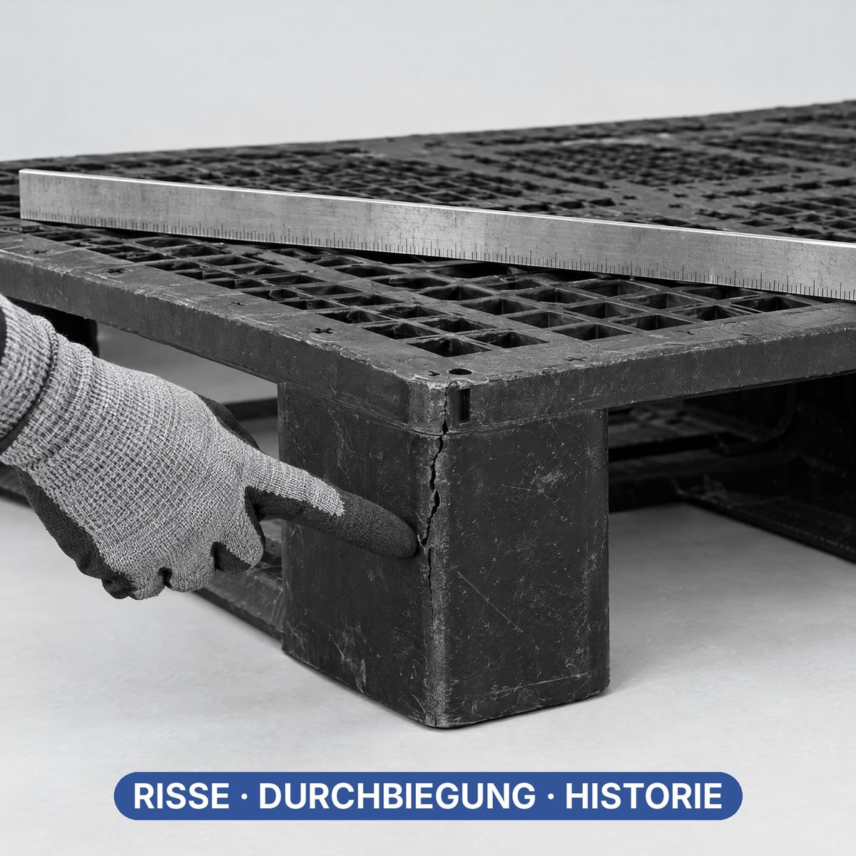 Hand zeigt auf einen Riss am Fuß einer gebrauchten Kunststoffpalette